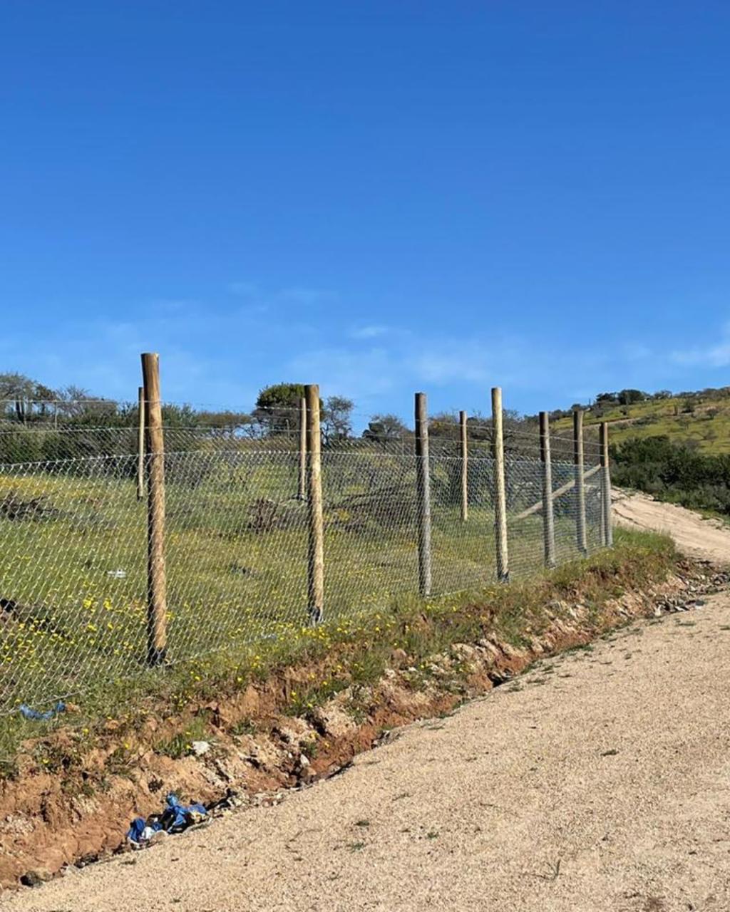 Cerco de malla galvanizada junto a camino rural, VI Región